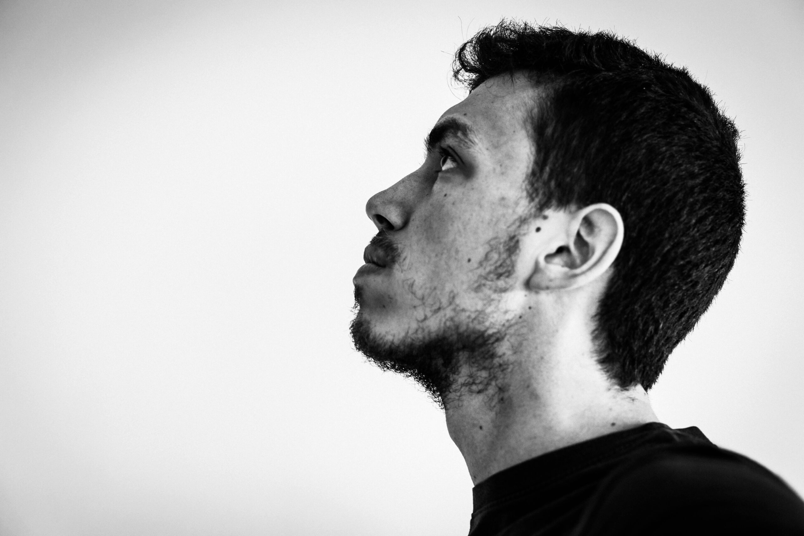 Contrasting black and white side view portrait of a contemplative young man.